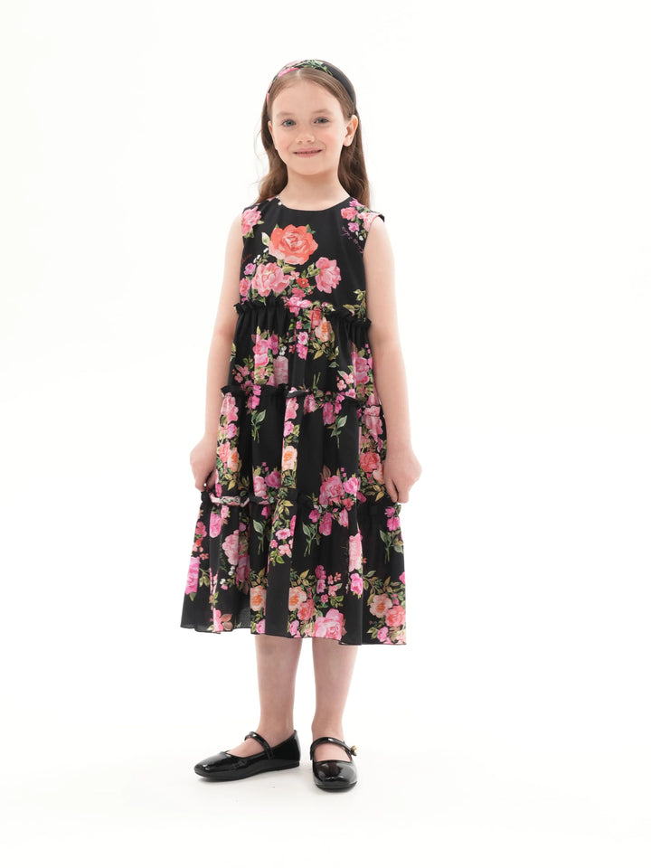 ALISA, A CHILDREN'S DRESS IN BLACK ADORNED WITH MEDIUM-SIZED PINK FLOWERS.