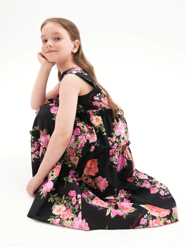 ALISA, A CHILDREN'S DRESS IN BLACK ADORNED WITH MEDIUM-SIZED PINK FLOWERS.