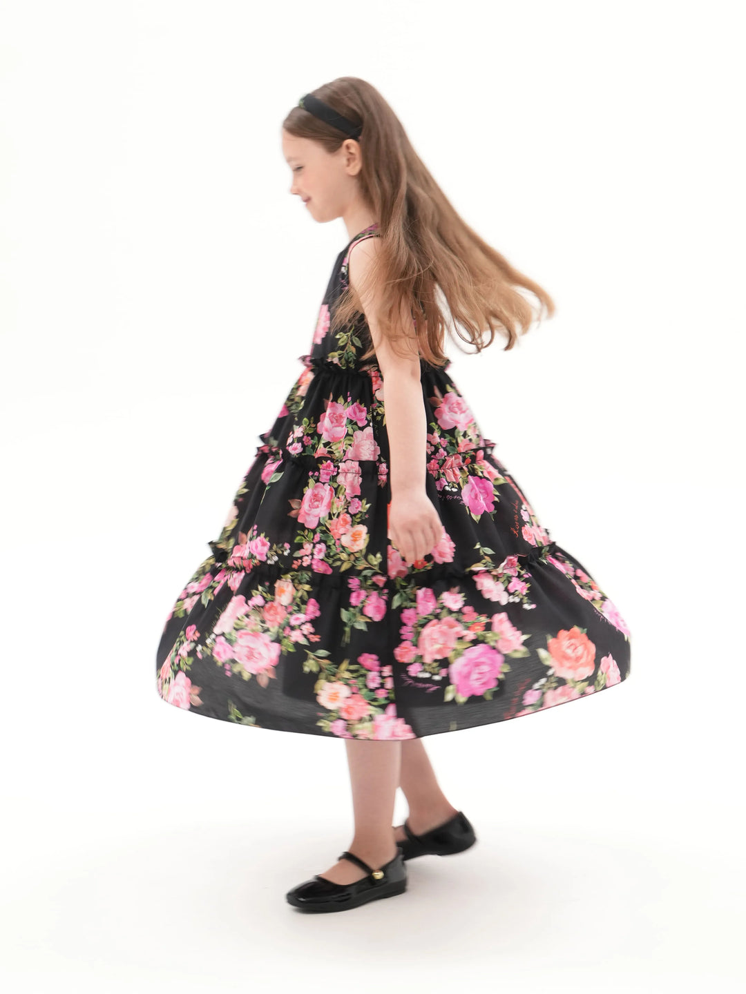 ALISA, A CHILDREN'S DRESS IN BLACK ADORNED WITH MEDIUM-SIZED PINK FLOWERS.